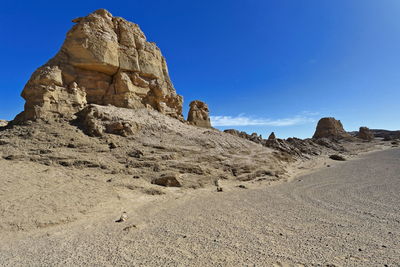 View of rock formations on landscape against blue sky