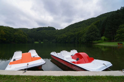 Boat moored by lake against sky