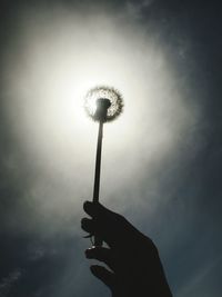 Low angle view of hand holding silhouette against sky