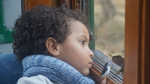 Close-up of cute boy looking through train window