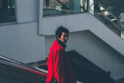 Side view of mature woman wearing red overcoat in city