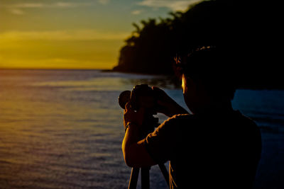 Silhouette man standing at beach during sunset