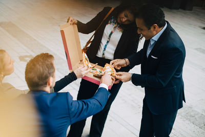 High angle view of business coworkers are eating pizza from box in city