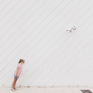 Girl standing on street against wall
