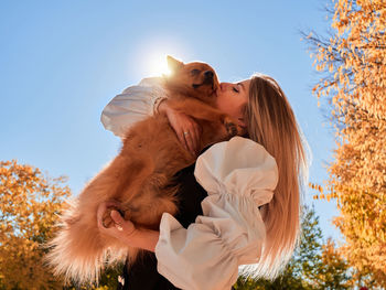 Young woman with dog against sky