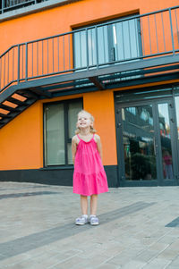 Portrait of young woman standing against building