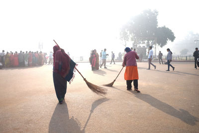 Women sweeping street in city