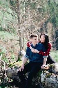 Smiling girlfriend embracing boyfriend in forest