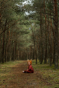 Toddler baby girl in bear bonnet sitting in the woods