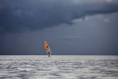 Person paragliding in sea against sky