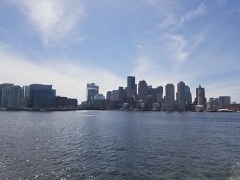 Sea by buildings against sky in city