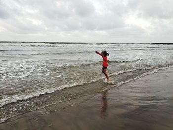 Full length of man standing on beach against sky