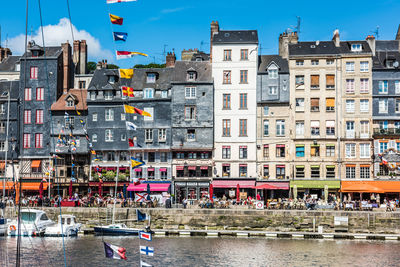 Boats in canal by buildings in city against sky