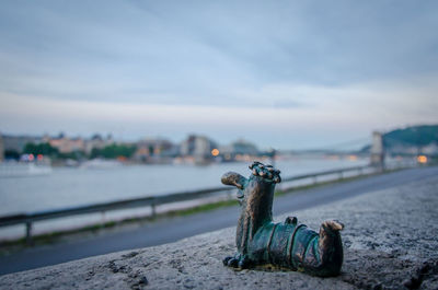 View of sculpture by river against sky