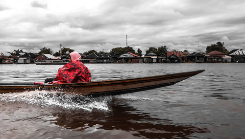 Man sailing on boat in river against sky