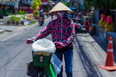 Rear view of woman with umbrella on street in city