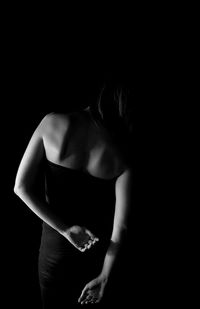 Close-up of woman touching hair over black background