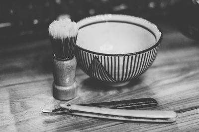 Close-up of shaving brush with razor and bowl on table