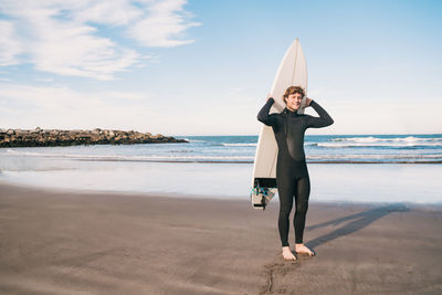 Portrait of smiling man with surfboard standing at beach