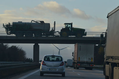 Vehicles on road against sky during sunset