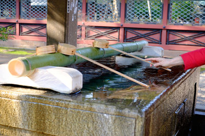 Cropped image of woman holding ladle at water fountain