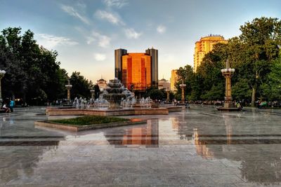 Fountain in lake against buildings in city