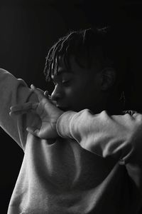 Close-up of young man standing against black background