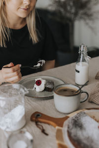 Woman eating chocolate cake with cream and raspberries