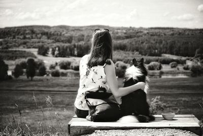 Rear view of woman with dog sitting on field