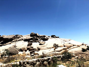 Rocks on landscape against clear blue sky