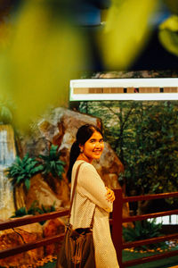 Portrait of young woman standing by railing