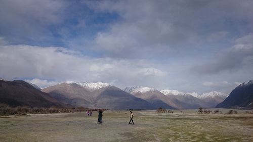 People on snowcapped mountains against sky