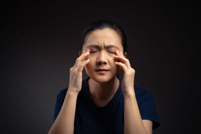 Portrait of young woman against black background