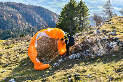 Man removing parachute tangled in bush on mountain