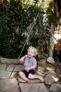 Full length of happy boy sitting outdoors