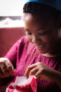 Close-up of smiling woman unwrapping gift box