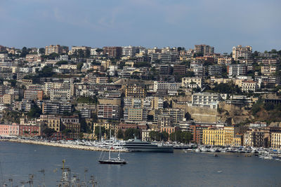 Aerial view of buildings by sea against sky