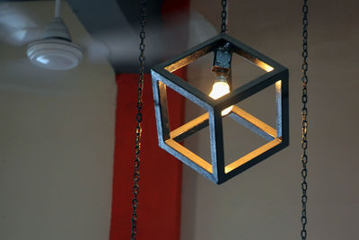 Low angle view of illuminated light bulb hanging at home