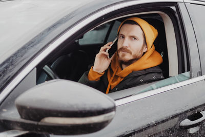 Millennial man drive the car and calling by smartphone. high quality photo