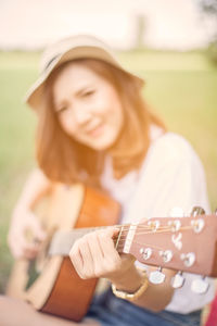 Young woman playing guitar on grassy field at park