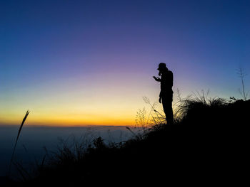 Silhouette man photographing at sunset