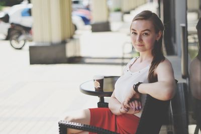 Portrait of young woman sitting on chair outdoors