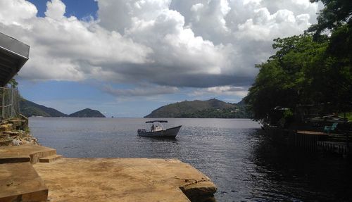 Boats in sea against cloudy sky