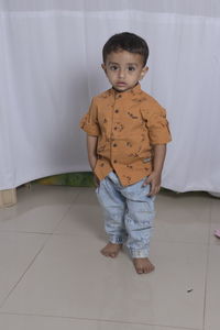 Portrait of boy standing on floor at home