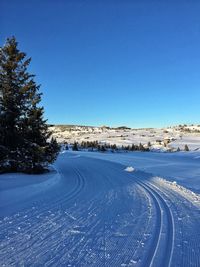 Scenic view of road against clear blue sky during winter