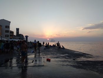 People on beach against sky during sunset