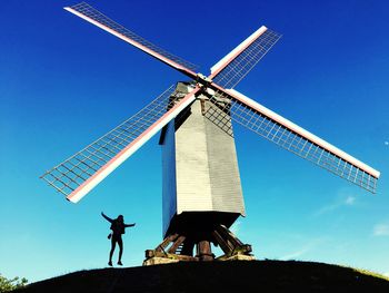 Low angle view of traditional windmill against clear blue sky