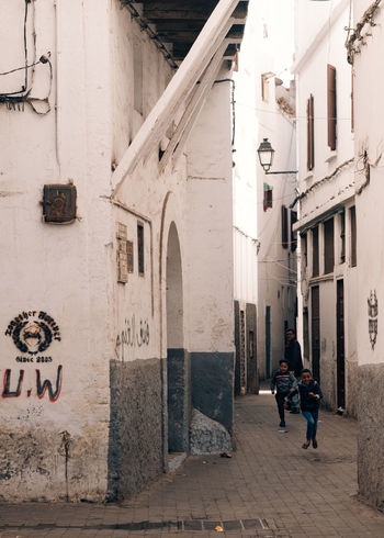 REAR VIEW OF PEOPLE WALKING ON BUILDING