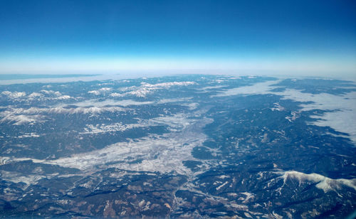 Aerial view of sea and mountains against blue sky