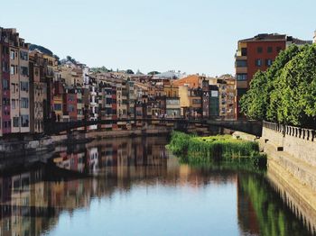 Reflection of buildings in river against clear sky